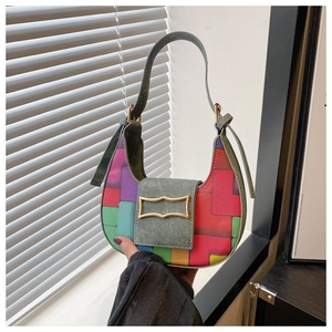 Detail of multi-color geometric patchwork saddle bag with green handle and gold metal buckle