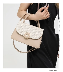 Detail of elegant beige leather handbag with white woven flap and round metal clasp