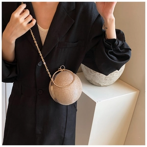 Detail of champagne gold spherical evening bag with glitter texture and metal ring handle