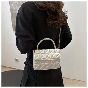 Silver quilted crossbody bag with golden chain strap shown on a female model