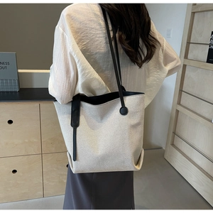 Detail view of large canvas tote bag with leather strap on model in minimalist room