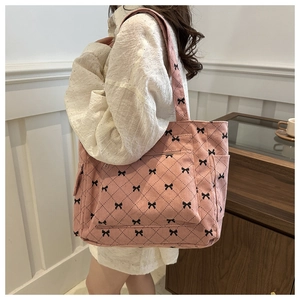 Pink corduroy tote bag with black bow print and quilted stitching shown on shoulder