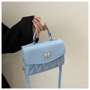 Detail of light blue crossbody bag with butterfly buckle and diamond quilted texture