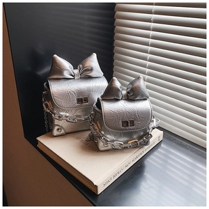 Detail of silver metallic mini bags with large bow and textured finish on books