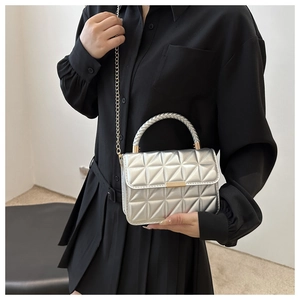 Detailed view of silver quilted leather bag with gold buckle and woven handle grip