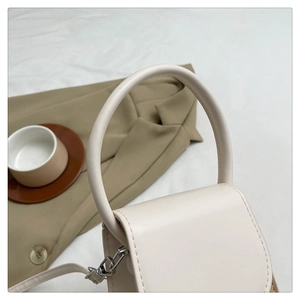 Detail of cream mini handbag showing round handle and straw woven side texture