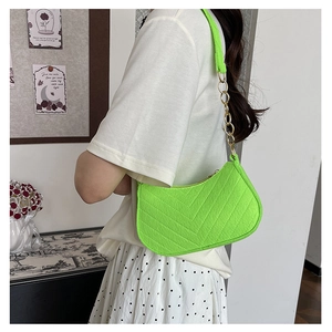 Detail view of neon green crescent shoulder bag with V-quilted faux leather and gold chain