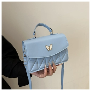 Detail of light blue quilted leather bag with a white butterfly buckle and top handle