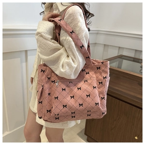 Detail of pink corduroy tote bag featuring black bow patterns and quilted stitching