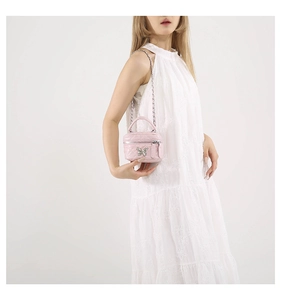 Pink quilted mini box bag with silver butterfly charm shown on a white dress model