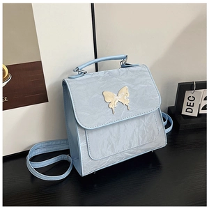 Detail of light blue wrinkled leather bag with decorative gold butterfly buckle