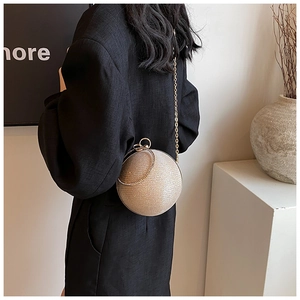 Champagne gold spherical clutch bag with round handle and chain strap on a model
