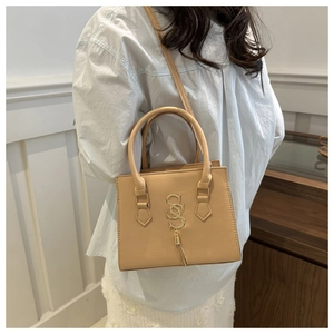 Detail of apricot square handbag with gold SS logo and elegant tassel charm