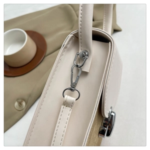 Detail shot of silver hardware and premium leather texture on a cream handbag