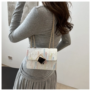 Detail of white chain bag featuring colorful embroidery and golden geometric metal lock