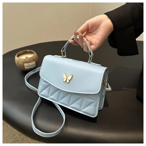 Close-up of light blue quilted mini bag with a gold butterfly clasp and top handle