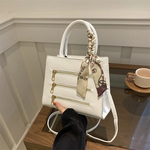 White minimalist square handbag with golden zippers and silk scarf handle detail