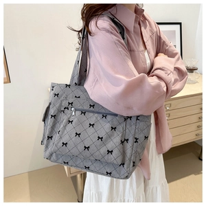 Detailed view of grey corduroy tote bag featuring black bow patterns and quilted texture