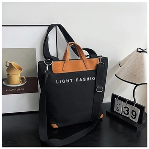 Detail view of large canvas tote bag with brown leather handles and adjustable shoulder strap