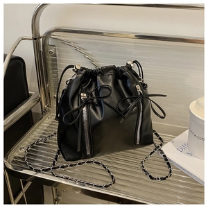 Detail of black drawstring bucket backpack with silver chain straps and decorative zippers