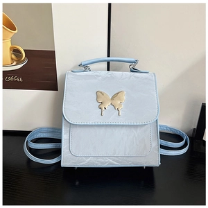Detail of light blue mini backpack showing gold butterfly buckle and pleated faux leather