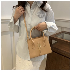 Chic beige crossbody bag with gold double S logo and tassel shown on a model