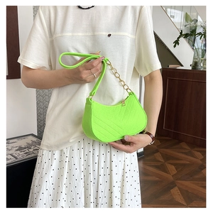 Detail of neon green crescent bag with quilted texture and golden chain strap