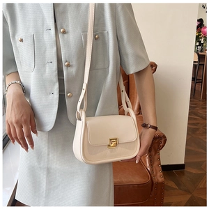 Detail of a cream-colored PU leather crossbody bag featuring a golden twist lock closure