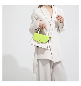 Détail d'un sac bandoulière blanc et vert lime porté avec un ensemble blazer chic blanc