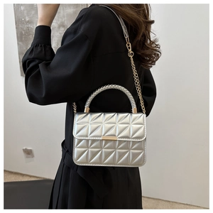 Detail of silver quilted crossbody bag with woven handle and gold chain strap