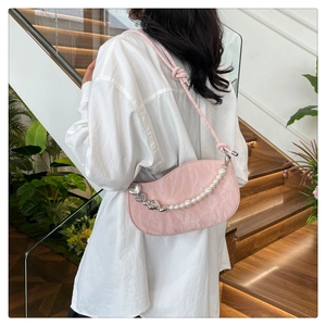 Detail of light pink pleated half-moon bag featuring pearl and heart chain on model