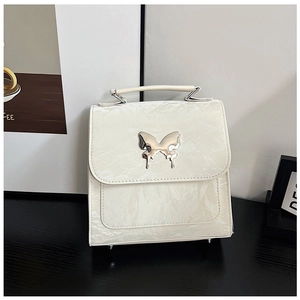Detail of silver butterfly metal buckle on white wrinkled patent leather handbag
