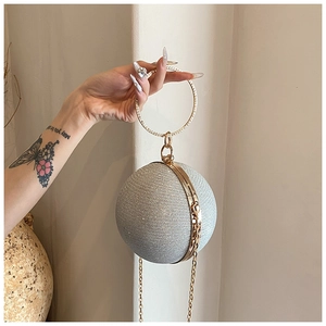 Detail of silver spherical evening bag with rhinestone handle and golden chain strap