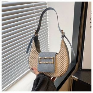 Detail of woven straw saddle bag with blue denim trim and golden metal clasp