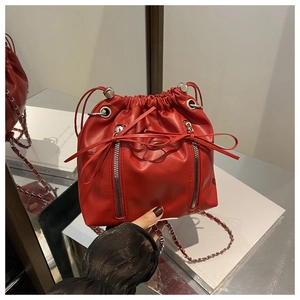 Detail view of red drawstring bucket backpack with silver metal chains and decorative zippers