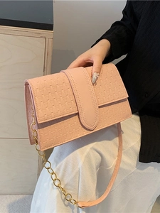 Pink flap handbag with woven texture and gold chain strap held by a model