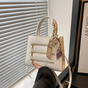 Detail of white leather handbag with triple zipper design and printed silk scarf handle