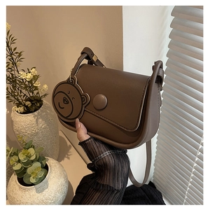 Détail du sac besace vintage marron foncé avec boucle ronde et charm d'ours mignon