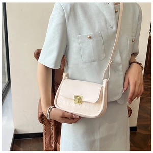 Detail of a creamy white crossbody bag with quilted pattern and gold metal buckle lock