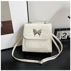 Detailed view of cream textured leather handbag featuring liquid metal butterfly ornament