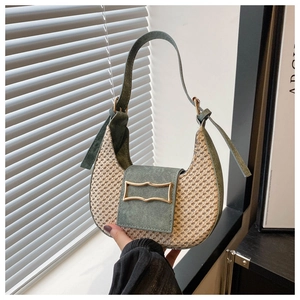 Detailed close-up of straw woven and green suede saddle bag with gold metal buckle