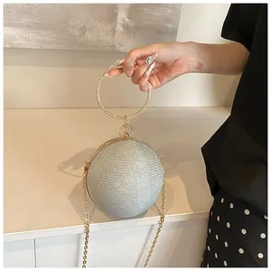 Close-up of a silver spherical evening clutch bag with glitter texture and gold ring handle