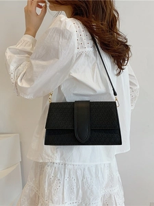 Elegant black flap handbag with 3D geometric texture and gold hardware on white lace
