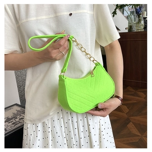 Detail of neon green crescent shoulder bag with quilted texture and gold chain link