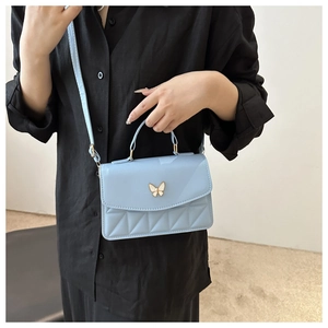Close-up of light blue quilted crossbody bag with golden butterfly clasp and top handle