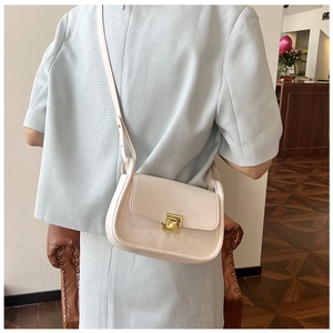 Detail of light beige crossbody bag featuring quilted patterns and golden twist lock closure