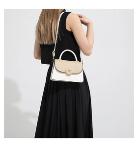 Gros plan sur la texture bicolore en simili cuir et la boucle ronde d'un sac à main chic