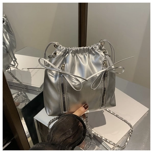 Detail of silver drawstring bucket backpack with shiny leather and bow accents