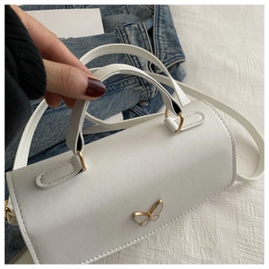 Detailansicht der weißen zylindrischen Handtasche mit goldener Schmetterlingsschnalle