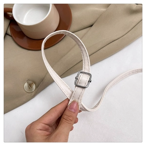 Detail of adjustable white leather shoulder strap with a silver metal buckle and fine stitching